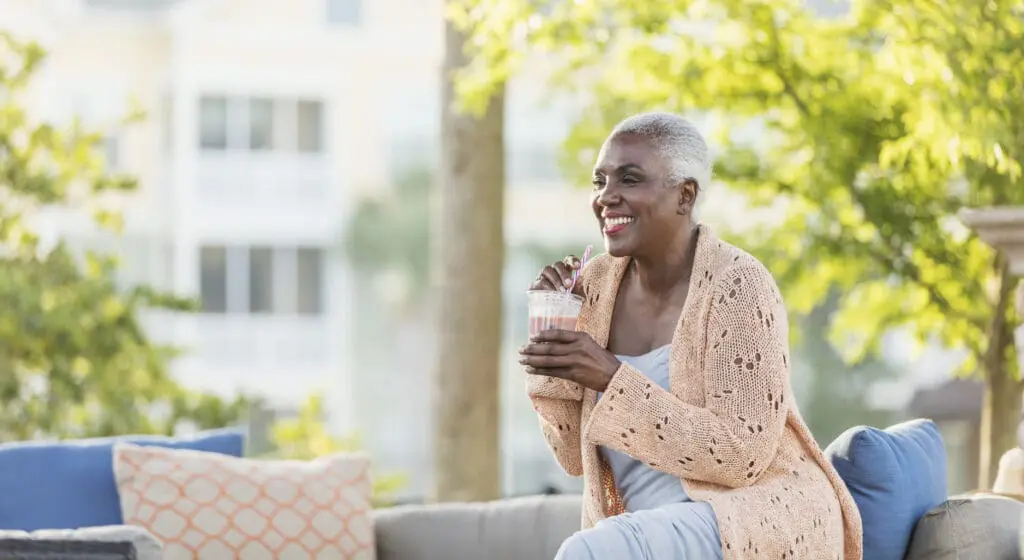 A senior African-American woman in her 60's relaxing outdoors on a sunny patio