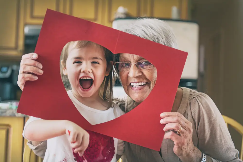 senior woman making a valentine's day craft with her young granddaughter