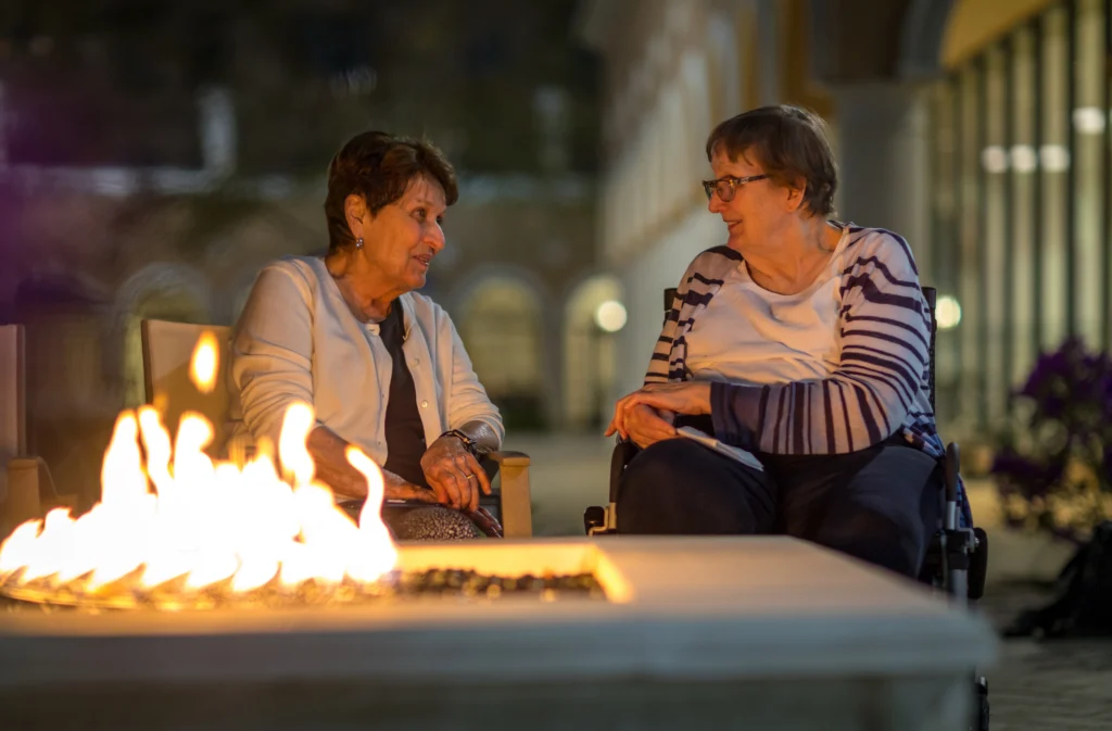 two senior women sit by fire pit at Windsor at Celebration