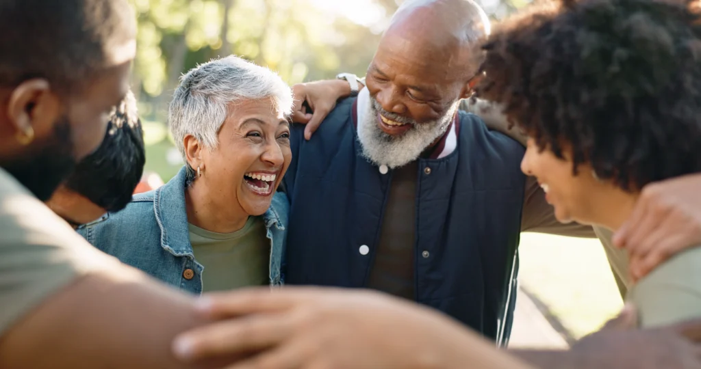 A group of senior residents at The Windsor at Celebration hugging and smiling about moving to Windsor at Celebration in Florida.