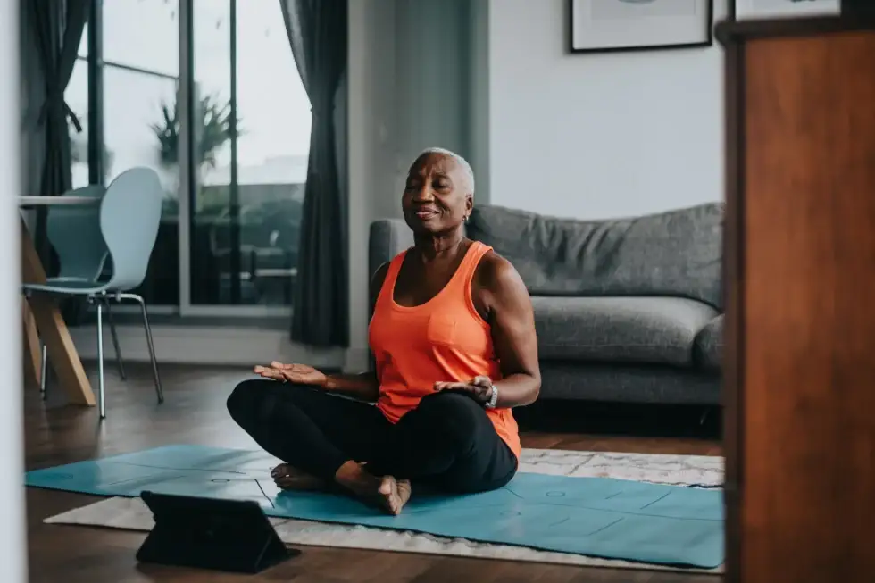 An elderly woman practicing yoga from the comfort of one-bedroom senior apartments available at Windsor at Celebration in Celebration, Florida.