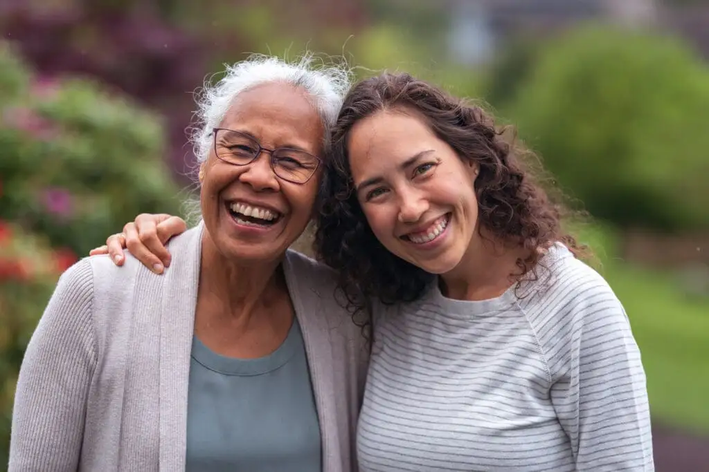 An adult woman hugging her elderly mother outside of Windsor at Celebration, after discussing a caring for aging parent checklist.