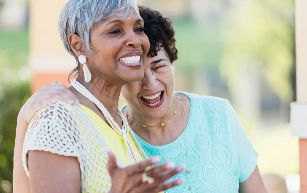 Two senior women hugging and laughing showing Senior Companionship at Windsor at Celebration in Florida.