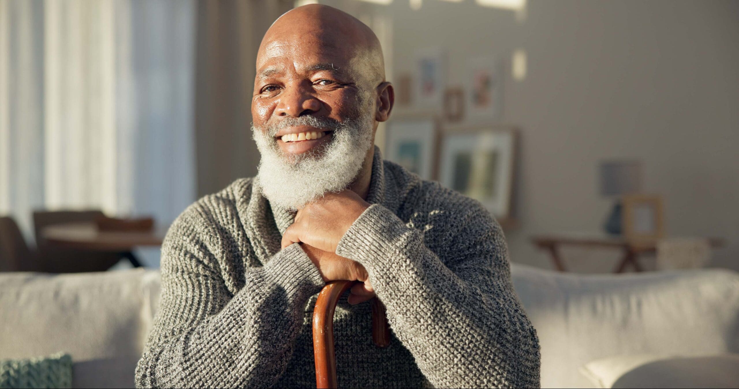 Senior man smiling with hands resting on cane